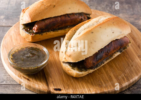 Choripan. Traditionelle Argentinien Sandwich mit Chorizo und chimichurri Sauce auf hölzernen Tisch Stockfoto