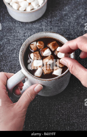 Eine Frau fügt Marshmallows zu einer Tasse heißen Johannisbrot-, eine kostenlose Alternative zu Schokolade. Stockfoto