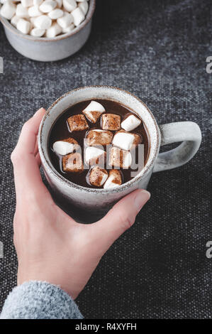 Eine Frau reicht für eine Tasse heißen Carob (natürlich Koffein frei) garniert mit Marshmallows. Stockfoto