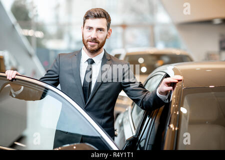 Porträt eines eleganten Geschäftsmann stand in der Nähe des Auto im Showroom Stockfoto