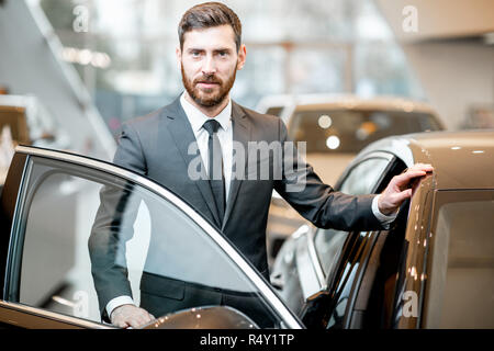 Porträt eines eleganten Geschäftsmann stand in der Nähe des Auto im Showroom Stockfoto