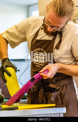 Männliche Chef Schneiden Aubergine in der Küche - mit Handschuh auf seiner Hand Stockfoto