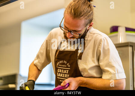 Männliche Chef Schneiden Aubergine in der Küche - mit Handschuh auf seiner Hand Stockfoto