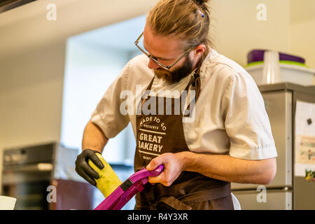 Männliche Chef Schneiden Aubergine in der Küche - mit Handschuh auf seiner Hand Stockfoto