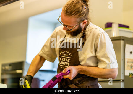 Männliche Chef Schneiden Aubergine in der Küche - mit Handschuh auf seiner Hand Stockfoto