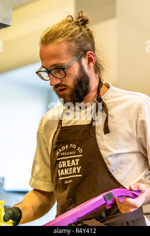 Männliche Chef Schneiden Aubergine in der Küche - mit Handschuh auf seiner Hand Stockfoto