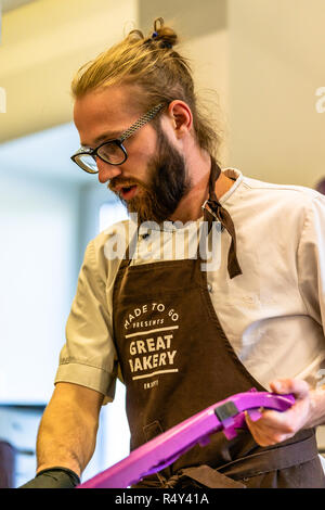 Männliche Chef Schneiden Aubergine in der Küche - mit Handschuh auf seiner Hand Stockfoto