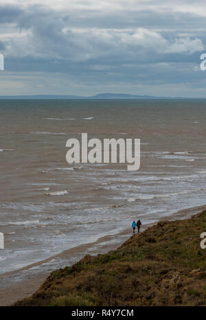 Menschen zu Fuß auf einer menschenleeren Strand auf der Insel Wight an einem Wintertag. Atmosphärische Meer und Küste auf der Insel Wight. Stockfoto