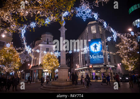 Malerische nächtliche Ansicht der funkelnden Weihnachtsbeleuchtung aufgereiht durch Bäume rund um das historische Seven Dials Monument, das sich in London, England, Großbritannien Stockfoto