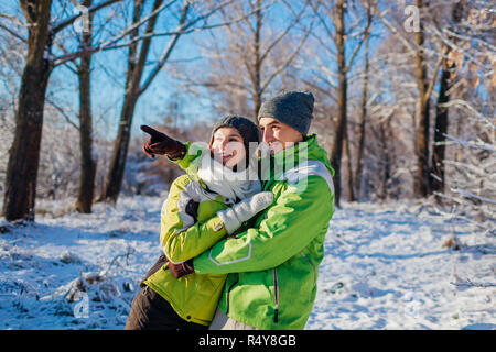 Glückliches Paar in der Liebe zu und umarmen im Winter Wald. Junge Menschen, die nach und suchen nach etwas Stockfoto