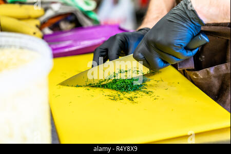 Männliche Chef Schneiden Dill am Gelben Brett - Küche Stockfoto