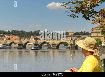 Prag, tschechische Republik - September 2018: weibliche Touristen tragen Sonnenhut mit Blick auf die Moldau und die Karlsbrücke in Prag. Stockfoto