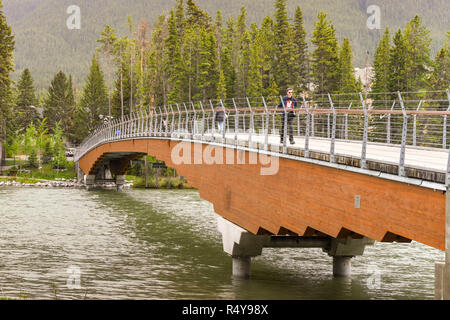 BANFF, AB, Kanada - Juni 2018: Person zu Fuß über eine Brücke über den Bow River in Banff. Stockfoto