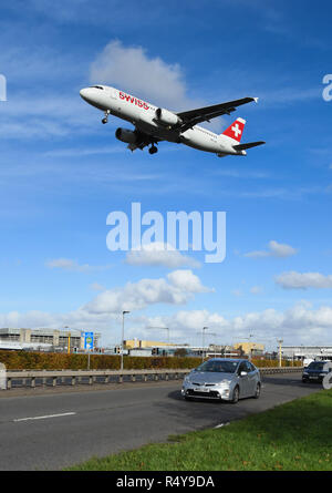 LONDON, ENGLAND - NOVEMBER 2018: Schweizer airliner in Land am Flughafen London Heathrow kommend über den Verkehr auf der A 30 Schnellstraße. Stockfoto