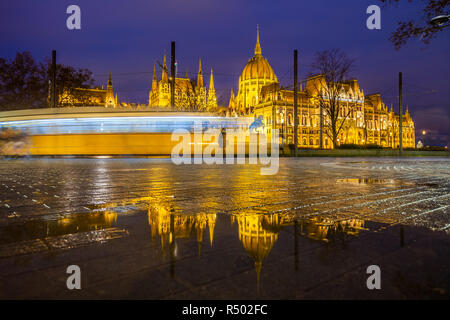 Budapest, Ungarn - beleuchtete Parlament Ungarns an der blauen Stunde mit Reflexion und traditionellen gelben Straßenbahn unterwegs