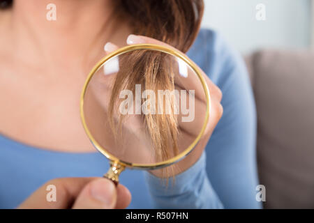 Frau an Ihren Haaren durch die Lupe suchen Stockfoto