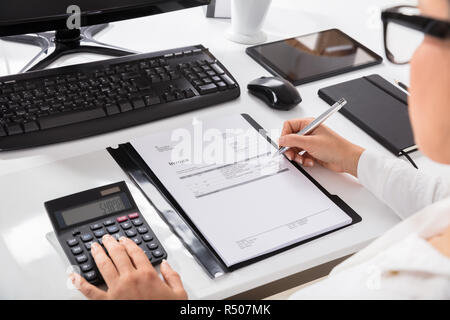 Mit Taschenrechner bei Berechnung auf der Rechnung Geschäftsfrau Stockfoto