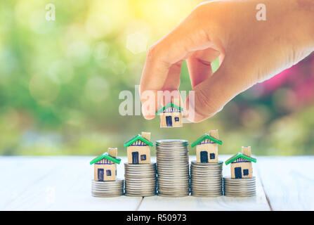 Haus auf Münzen Männer hand Planung spart Geld der Münzen eine Home Konzept Konzept für property Ladder, Hypotheken und Immobilien zu kaufen, investieren. Stockfoto