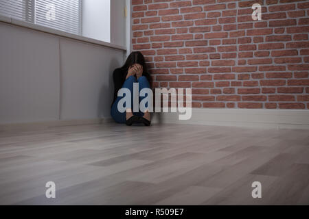 Fürchtete Frau sitzt an der Ecke Stockfoto