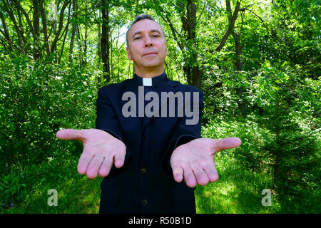 Ein katholischer Priester uns ist einladend in der Freude. Er schaut mit Vertrauen an uns, seine Arme öffnen in Frieden. Stockfoto