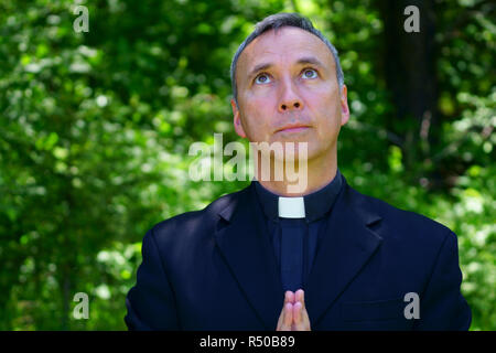 Ein katholischer Priester ist Gott beten. In den Himmel schauend. Er blickt zuversichtlich. Stockfoto