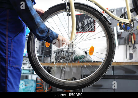 Mann strafft und schmiert das Schaltwerk in das Fahrrad Stockfoto