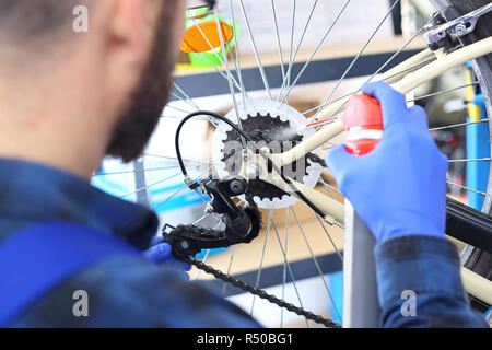 Fahrrad, Reparatur und Wartung. Fahrrad Service, Installation Umwerfer Mann strafft und schmiert das Schaltwerk in den Bike serviceman. Der Mann repariert das Fahrrad Fahrrad reparieren Fahrrad Service, Fahrrad reparieren Stockfoto