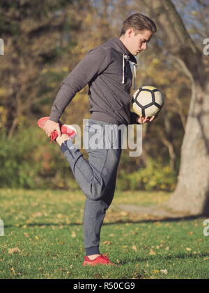 Fußballspieler, die sich mit Fußball im Park an einem sonnigen Herbsttag Stockfoto