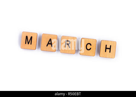 März, Dinkel mit hölzernen Buchstabensteine über einen weißen Hintergrund. Stockfoto