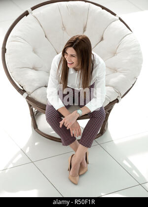 Müde junge Frau in gemütlicher Runde Stuhl Stockfoto