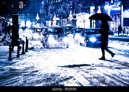 Blurry verschneite Stadt Nacht Verkehr mit Fußgänger-silhouete Überqueren der Straße Stockfoto