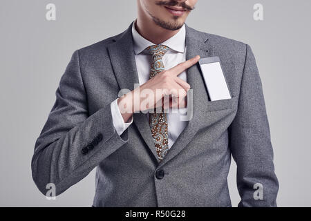 Close-up Portrait von gutaussehenden Jungen zuversichtlich arabischer Geschäftsmann mit ausgefallenen Schnurrbart in Mode grauen kompletten Anzug versteckt sich das Telefon in seiner Hosentasche auf Studi Stockfoto