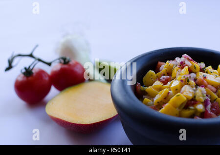 Mango Salsa in einem Stein Schüssel mit Zutaten in den Hintergrund Stockfoto