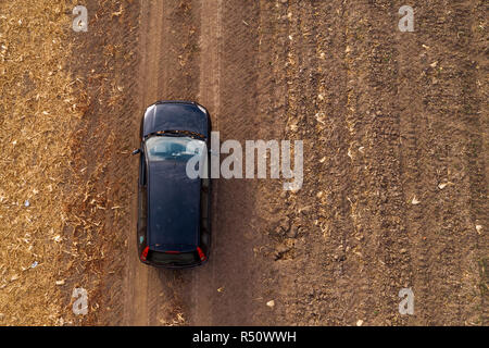 Luftaufnahme von Schwarze Auto auf unbefestigte Straße durch Landschaft, Blick von oben auf die Off-road Fahren des Fahrzeugs von Drone pov Stockfoto