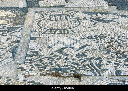 Ostia Antica in Rom, Italien. Mosaik auf dem Shop Floor auf der Piazzale delle Corporazioni mit Hakenkreuz eine geometrische Figur und einem alten religiösen Symbol Stockfoto