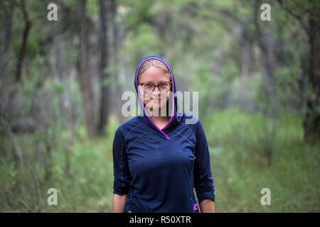 Vorderansicht Taille bis Portrait von weiblichen Bootsführer in blau Hooded Sweatshirt und Brillen in Wald Stockfoto