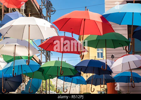 Eine Gruppe von Sonnenschirmen an den Drähten hängen bunte draußen auf der Straße in Bergen, Norwegen. Stockfoto