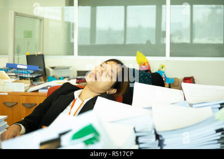 Erschöpft Geschäftsfrau schlafen auf dem Schreibtisch im Büro mit Haufen von paperwok. Stockfoto
