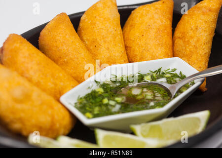 Typische kolumbianischen Empanadas serviert mit pikanter Sauce auf traditionelle schwarze Keramik Teller Stockfoto