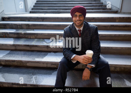 Portrait von indischer Geschäftsmann sitzt auf der Treppe im Freien in der Stadt Stockfoto
