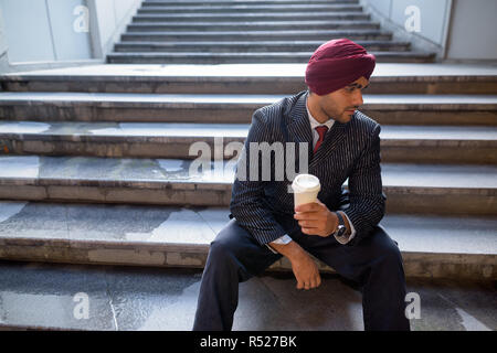 Portrait von indischer Geschäftsmann sitzt auf der Treppe im Freien in der Stadt Stockfoto