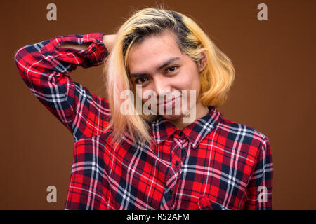 Jungen asiatischen Mann, stilvolle Kleidung gegen braunen Hintergrund Stockfoto