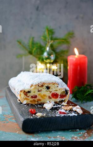Dresdner Stollen mit Rosinen, getrocknete Aprikosen, getrocknete Kirschen, Nüssen und kandierten Früchten in Zucker Glasur auf einer festlichen Hintergrund. Lecker Stockfoto