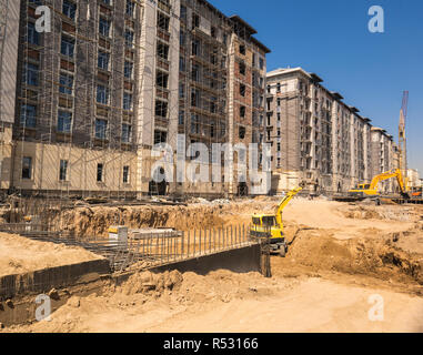 Auf der Baustelle Bagger gräbt eine Grube im Boden Stockfoto