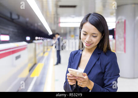 Geschäftsfrau mit Handy in Zug Plattform Stockfoto