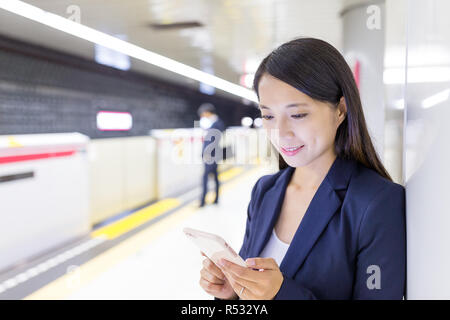 Geschäftsfrau Arbeiten am Handy in Zug Plattform Stockfoto