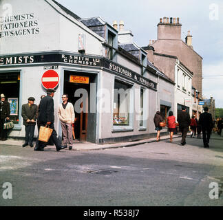 1960, historische, Tages- und lokalen Personen außerhalb eines Shop von R. Smith Ltd, Chemiker, Stationers und Zeitungsläden in Stornoway, Lewis, Isle of Lewis und Harris, Äußere Hebriden, Western Isles, Schottland, Großbritannien. Stockfoto