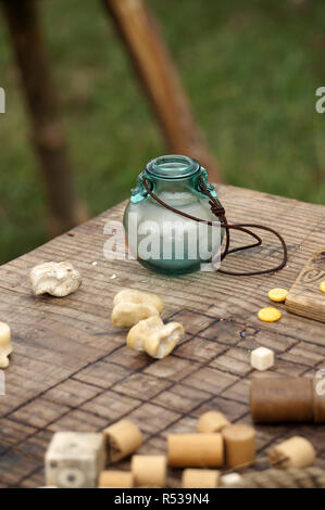 Ein kleines Glas Glas mit einem Lederband, auf einer hölzernen Spielbrett. Stockfoto