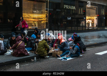 Weibliche Arbeitnehmer aus Indonesien und den Philippinen Treffen am Sonntag auf den Straßen von Hong Kong Central in der Nähe der luxuriösen Geschäften. Hong Kong, Januar 2018 Stockfoto