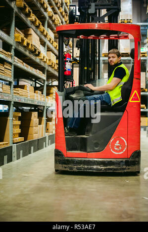 Junger Mann in Arbeitskleidung, Treiber Schubmaststapler arbeitet auf der Logistik Lager store Stockfoto